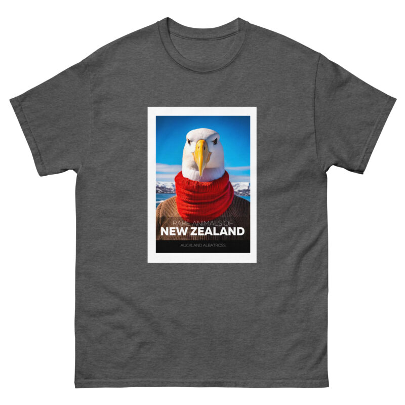 A gray t-shirt showcases an illustration of an albatross adorned with a red scarf, set against a background of a blue sky and mountain landscape. The text reads, "Rare Animals - Auckland Albatross.